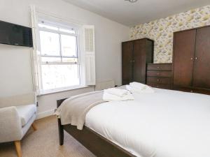 um quarto com uma grande cama branca e uma janela em Leo's Place em Weymouth