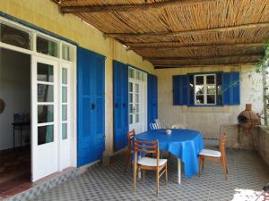 uma mesa e cadeiras num pátio com portas azuis em maison calme et reposante em Essaouira