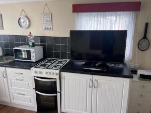 a kitchen with a stove and a microwave at Chalet 71 in Leysdown-on-Sea