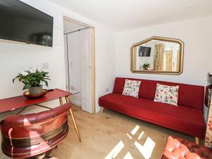 a living room with a red couch and a mirror at Garden Suite in Dronfield