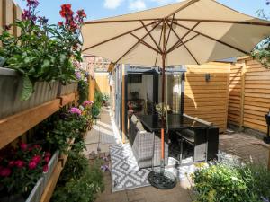 un patio con sombrilla, mesa y sillas en Garden Suite en Dronfield