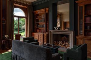 a living room with a fireplace and two chairs at Cowley Manor Experimental in Cheltenham