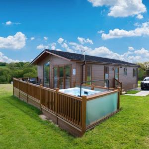 a house with a large hot tub in the yard at Meadow Lakes Holiday Park in Grampound