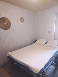 ein leeres Bett in einem Zimmer mit einer Wand in der Unterkunft Le petit paradis iodé in Gujan-Mestras