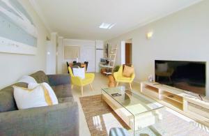 a living room with a couch and a television at Ursula's Upmarket Apartment - Panoramic Views, Large Patio - Braai, WIFI - DSTV in Plettenberg Bay