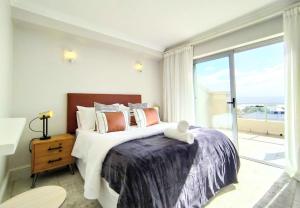 a bedroom with a large bed and a large window at Ursula's Upmarket Apartment - Panoramic Views, Large Patio - Braai, WIFI - DSTV in Plettenberg Bay