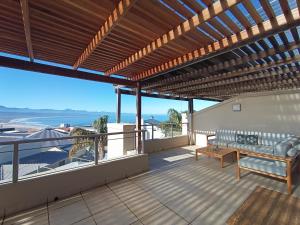 a balcony with a couch and a view of the ocean at Ursula's Upmarket Apartment - Panoramic Views, Large Patio - Braai, WIFI - DSTV in Plettenberg Bay