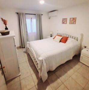 1 dormitorio con 1 cama grande con sábanas blancas y almohadas de color naranja en Casa en Salta en Salta