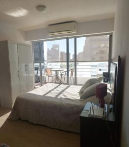 1 dormitorio con 1 cama y balcón con mesa en Edificio Go Pocitos, en Montevideo