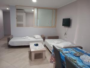 Cette chambre comprend 2 lits, une table et un miroir. dans l'établissement Eleana's Apartament, à Saranda