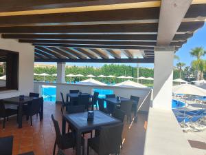 un restaurant avec des tables et des chaises ainsi qu'une piscine dans l'établissement Residence Hydria, à Campofelice di Roccella