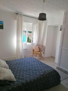 ein Schlafzimmer mit einem Bett und einem Stuhl und Fenstern in der Unterkunft Gite à 5mn des plages et à 5mn de Granville in Longueville