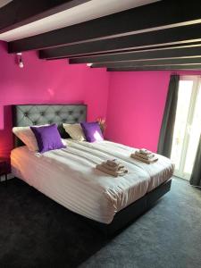 um quarto rosa com uma cama grande e almofadas roxas em B&B with or without Schutter 7 em Zierikzee