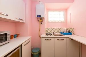 a pink kitchen with a sink and a microwave at Holiday House Esedra in Rome