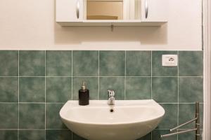 a white sink in a bathroom with green tiles at Holiday House Esedra in Rome
