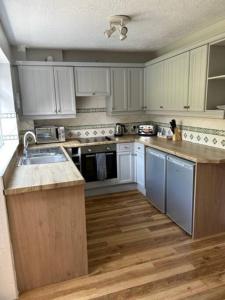 - une cuisine avec des placards blancs et un évier dans l'établissement Workers & Visitors- Gainford 4Bedrooms, à Walsgrave on Sowe