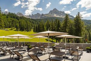 a bunch of chairs and umbrellas on a patio at Sporthotel Obereggen in Obereggen
