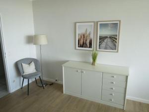 um quarto branco com uma cadeira e uma cómoda em BTSD59302-FeWo-Stranddistel-IV em Burgtiefe auf Fehmarn 