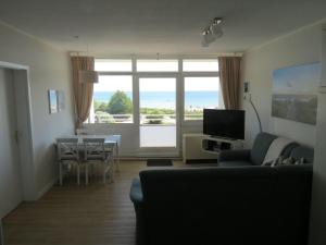 uma sala de estar com um sofá, uma mesa e uma televisão em BTSD59302-FeWo-Stranddistel-IV em Burgtiefe auf Fehmarn 