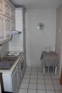 uma cozinha com armários brancos, um lavatório e uma mesa em BTSD59302-FeWo-Stranddistel-IV em Burgtiefe auf Fehmarn 