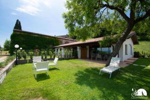 un patio con dos sillas blancas y un árbol en Il Podere del Bardo, en Puegnago sul Garda
