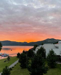 um pôr-do-sol sobre uma massa de água com um edifício em L57_resort em Gródek Nad Dunajcem