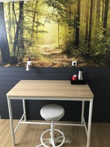 un escritorio de madera con una silla frente a una pintura de un bosque en dardennen en La-Roche-en-Ardenne