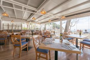 a restaurant with wooden tables and chairs and windows at Hotel Tamariu in Tamariu