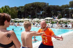 a man holding a bat at a swimming pool at Fabulous village in Casal Palocco