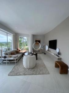 a white living room with a couch and a tv at Villa design vue panoramique in Grabels