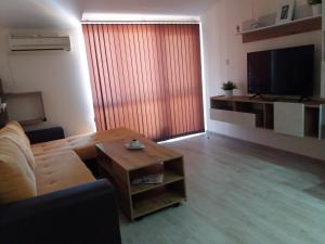 a living room with a couch and a table and a television at Апартамент в комплекс Зора 9A in Sozopol