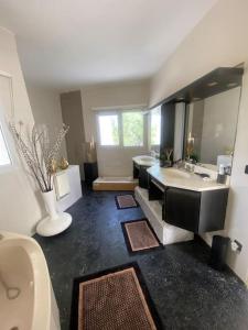 a bathroom with two sinks and a tub and a large mirror at Villa design vue panoramique in Grabels