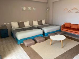 2 Betten in einem Zimmer mit einem Tisch und einem Sofa in der Unterkunft el Bulli Inn in Hualien