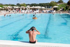a man sitting in the water at a swimming pool at Fabulous village in Casal Palocco