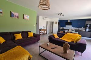 uma sala de estar com um sofá castanho e almofadas amarelas em Gîte la Couzinette 3km du parc Puy du Fou em Les Épesses