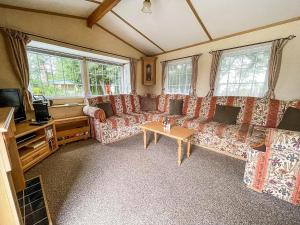 a living room with couches and a table and a tv at Superb Caravan With Decking At Southview Holiday Park Ref 33093s in Skegness