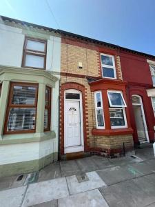 una casa de ladrillo rojo con una puerta blanca en una calle en Charming newly renovated terrace en Liverpool
