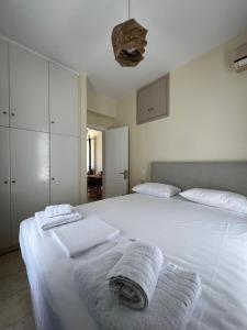 a bedroom with a large white bed with towels on it at Anoixi Apartments in Korissia