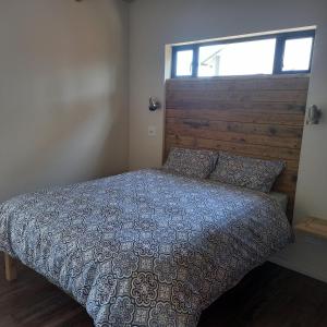 a bedroom with a bed with a wooden headboard and a window at Let the good times roll-with inverter and wifi in Cape St Francis +31 photos