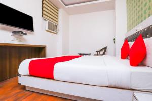 1 dormitorio con 1 cama con almohadas rojas y TV en OYO Hotel Sehej Continental, en Nueva Delhi
