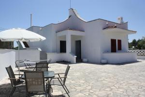 een patio met een tafel en stoelen en een parasol bij La Mia Villa in Ceglie Messapica