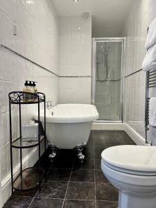 a white bathroom with a tub and a toilet at Coed Mawr Hall Bed & Breakfast in Conwy