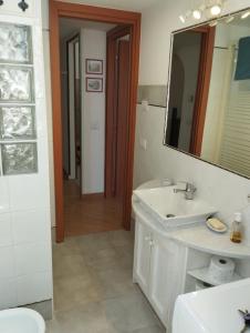 ein weißes Badezimmer mit einem Waschbecken und einem Spiegel in der Unterkunft MI CASA TU CASA in Civitavecchia