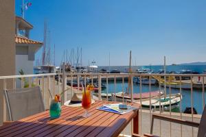 a wooden table with two cocktails on a balcony with a marina at Duplex à La Marina in Saint-Raphaël
