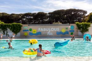 a group of people in the water at a swimming pool at Fabulous village in Casal Palocco
