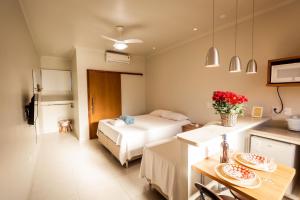 una habitación de hotel con una cama y una mesa con flores en Suites em Jabaquara, Paraty, en Paraty