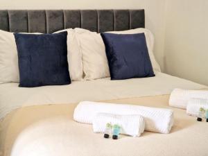 ein Bett mit weißen Handtüchern und blauen Kissen darauf in der Unterkunft St Johns House in Burnley