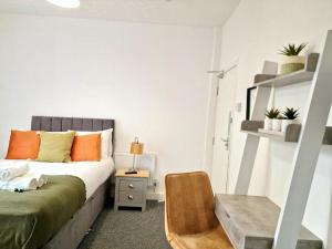 ein Schlafzimmer mit einem Bett mit orangefarbenen Kissen und einem Stuhl in der Unterkunft St Johns House in Burnley