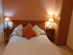 a bedroom with a bed with pillows and two lamps at Hostal Can Massot in Anglés