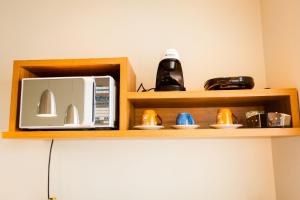 a microwave on a wooden shelf next to a kitchen at Suites em Jabaquara, Paraty in Paraty